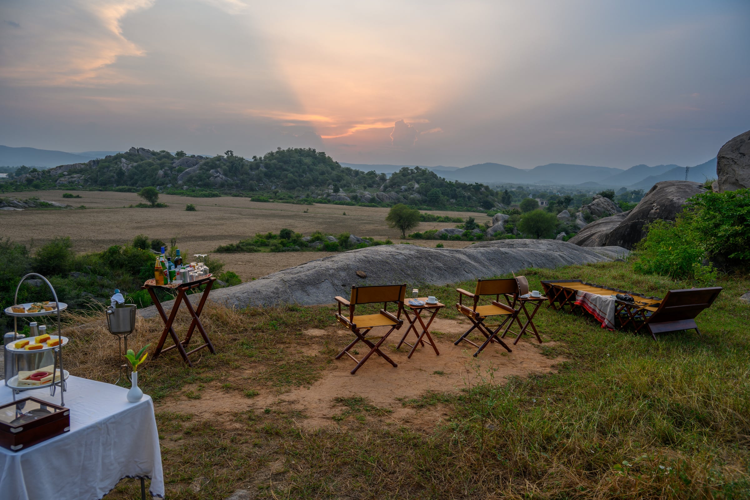 An image of an outdoor seating amidst greenery over viewing the mountains - Utsav Camp Sariska.