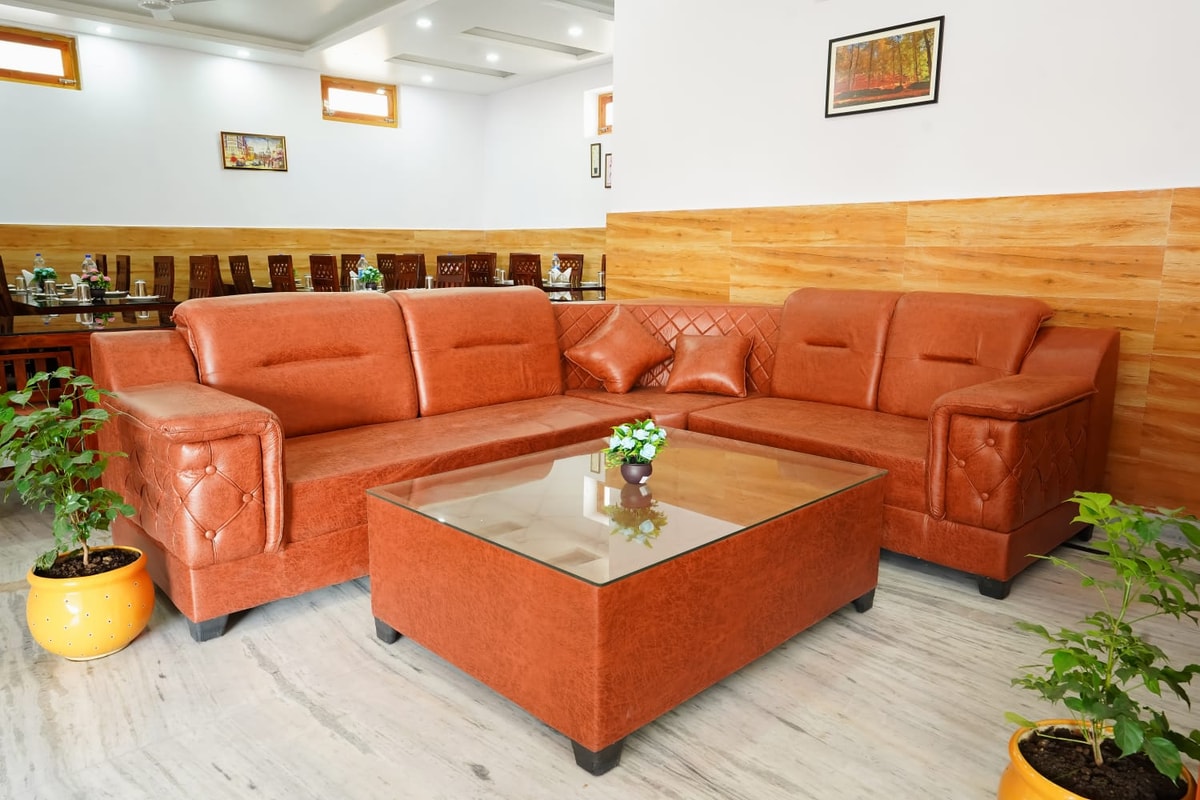 Lobby seating area at Hotel Sparrow Dharamshala — brown leather sofa with coffee table