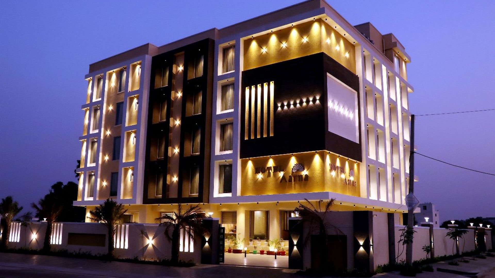 The lit façade of Hotel Aarna Premier, Jaipur after dark