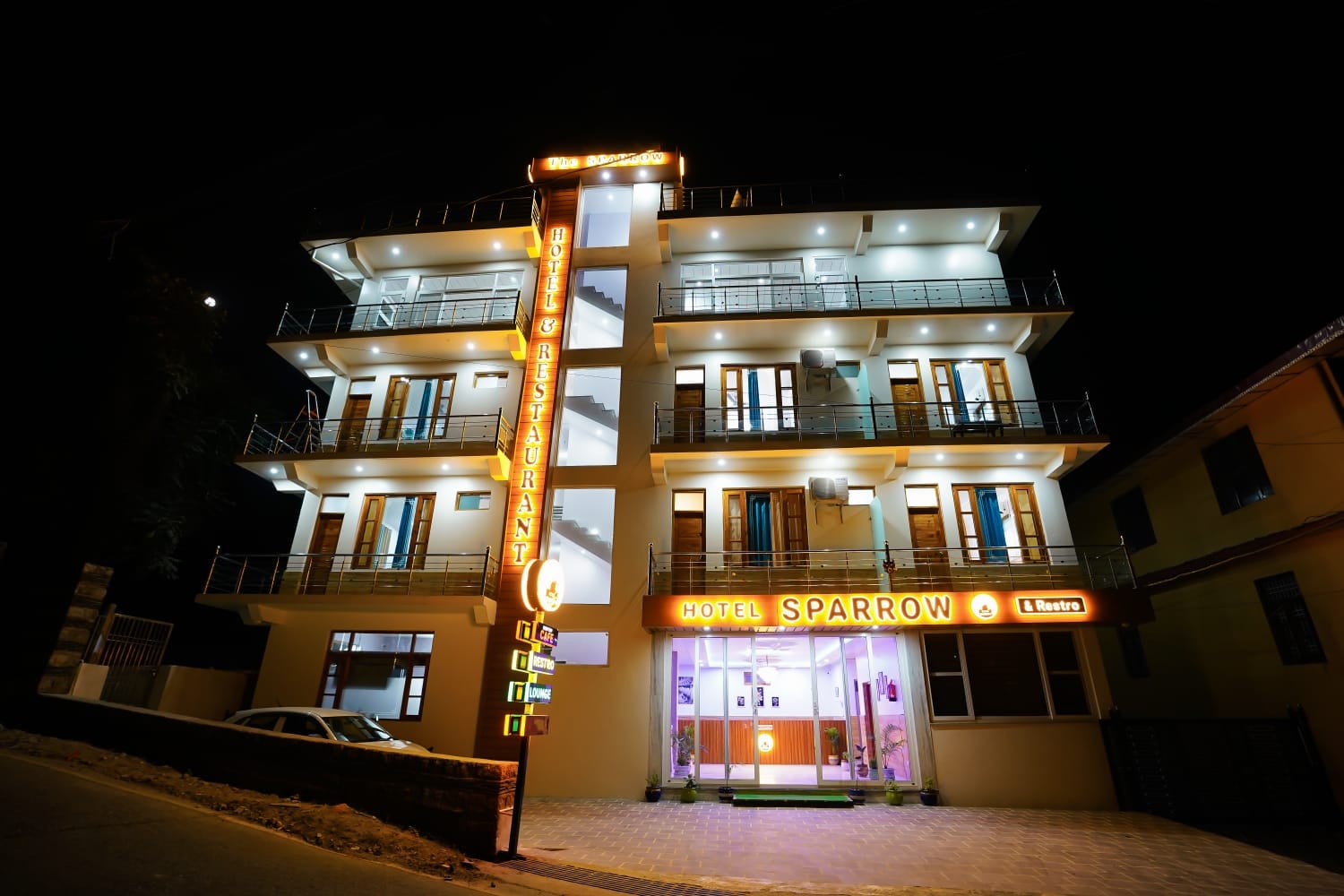 Hotel Sparrow Dharamshala at night with illuminated facade signage