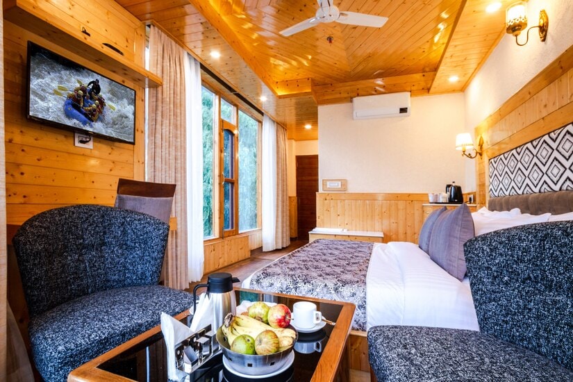 Deluxe Room at Hotel Suryansh Regency By Kavin Hotels, Manali, king bed, diamond-pattern headboard, blue armchairs, and air conditioning