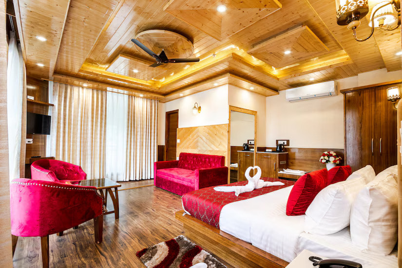 Luxury Room at Hotel Suryansh Regency By Kavin Hotels, Manali, king bed, red velvet seating, coffered wooden ceiling with star-burst lights