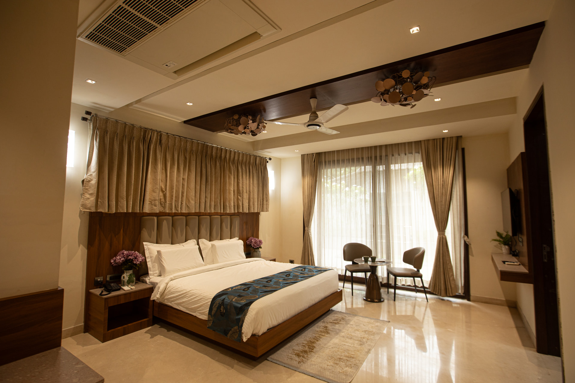 A king-size bed with warm wood panelling in the Executive Kitchenette at Rossedale Suites & Hotel in Peelamedu, Coimbatore