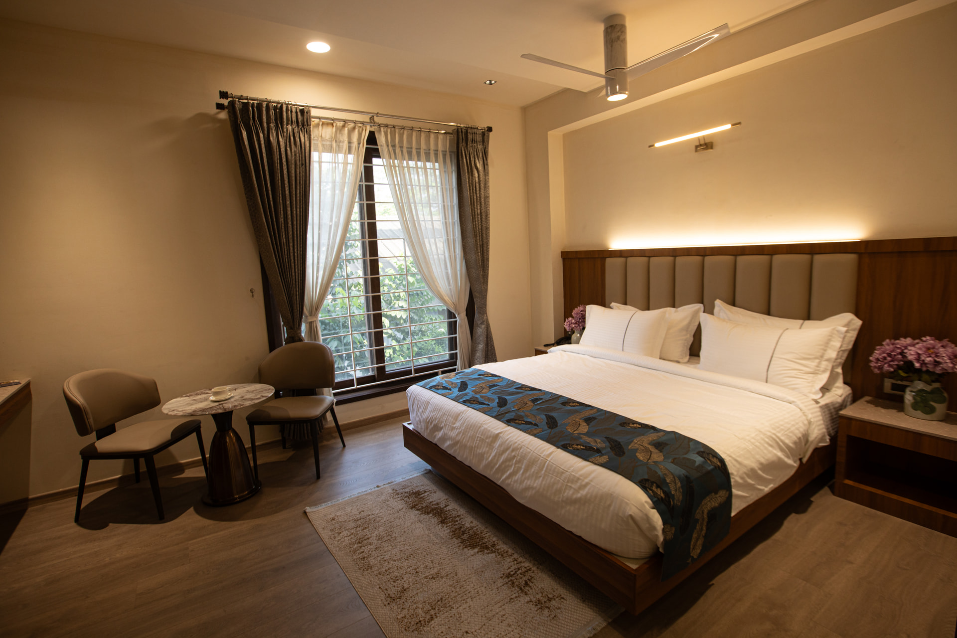 A king-size bed with warm wood panelling in the Family Suite at Rossedale Suites & Hotel in Peelamedu, Coimbatore