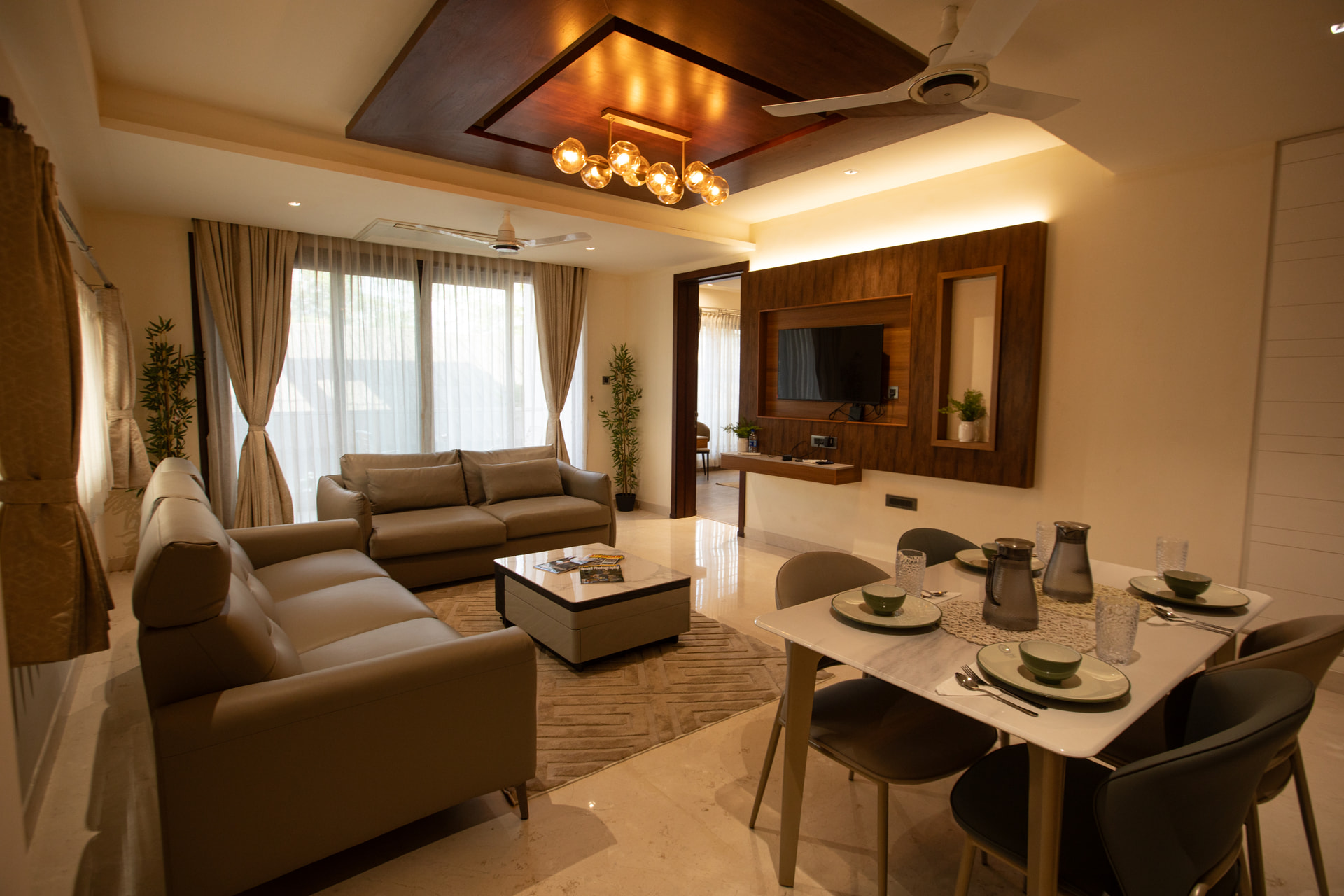 The separate living room of a Family Suite with sofas, a coffee table and a dramatic pendant light at Rossedale Suites & Hotel in Peelamedu, Coimbatore