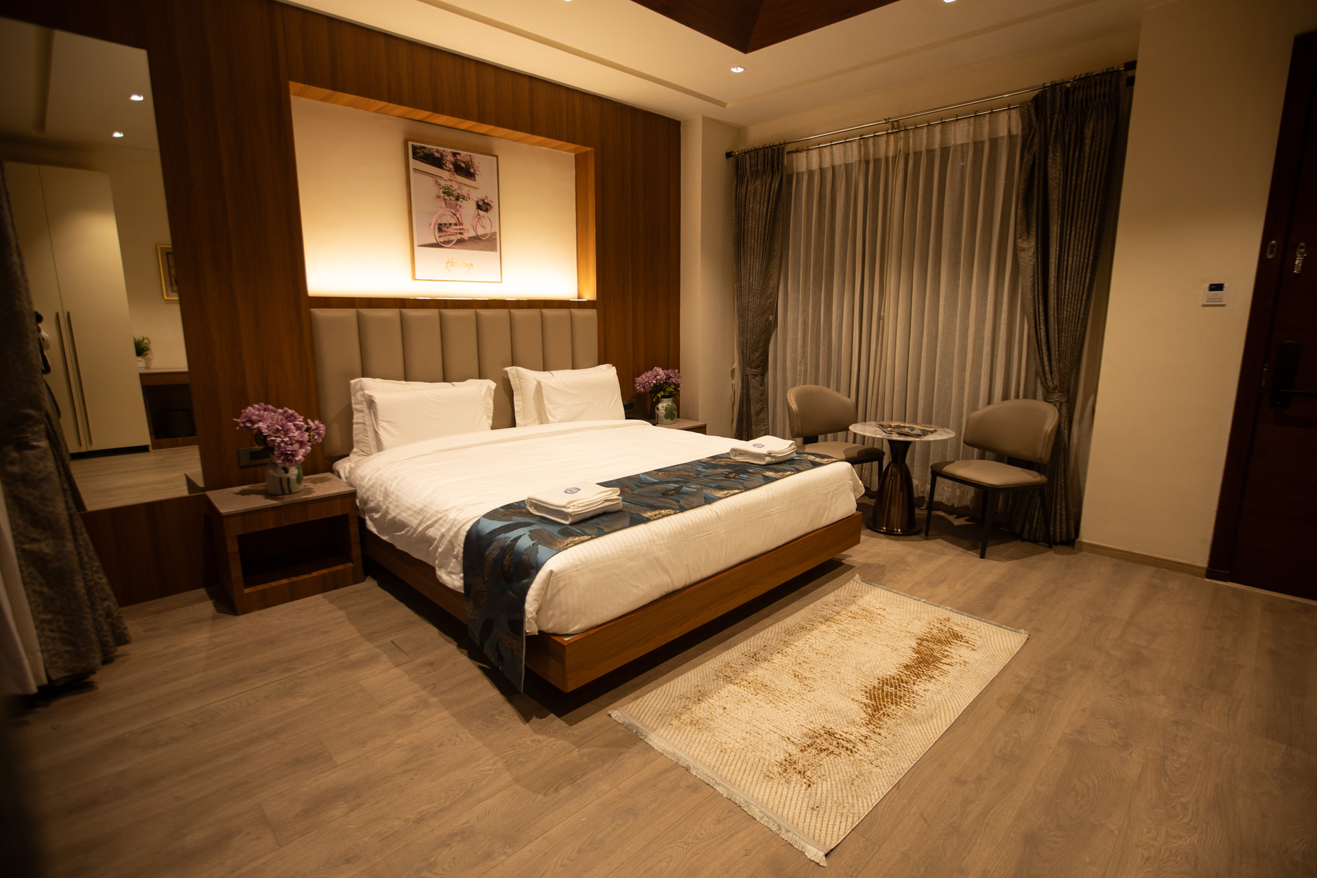 A king bed in the warmly lit Jacuzzi Room with timber panelling and soft mood lighting at Rossedale Suites & Hotel in Peelamedu, Coimbatore