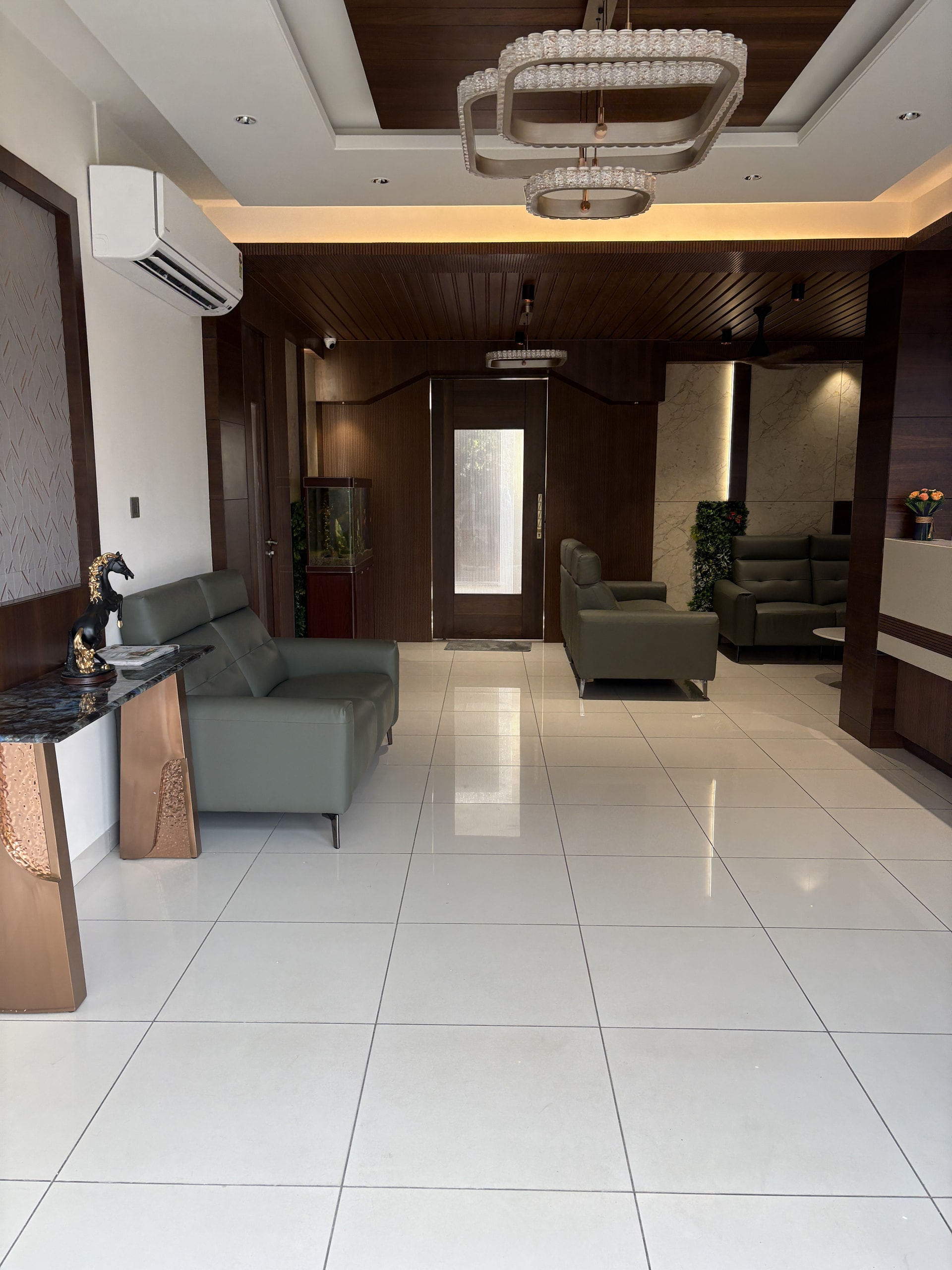 A quiet lobby lounge with cushioned armchairs and warm lighting beside the reception at Rossedale Suites & Hotel in Peelamedu, Coimbatore