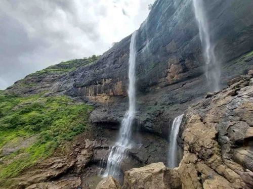 Waterfalls site showcasing water cascading down the rocky hills surrounded by trees.