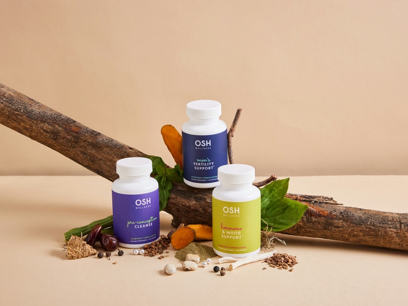 Three Ayurvedic supplement bottles arranged with a piece of branch, herbs, roots and spices on a beige background