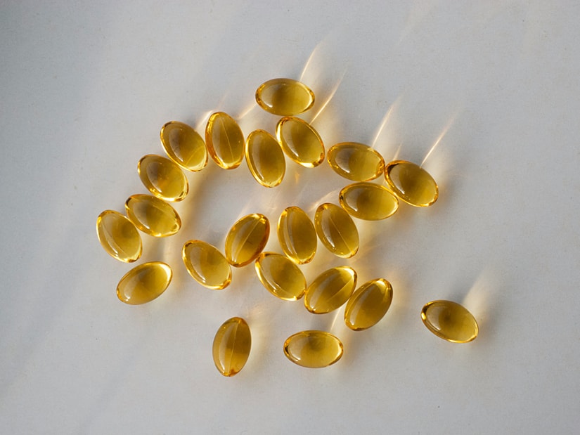 Golden fish oil capsules scattered across a pale grey surface