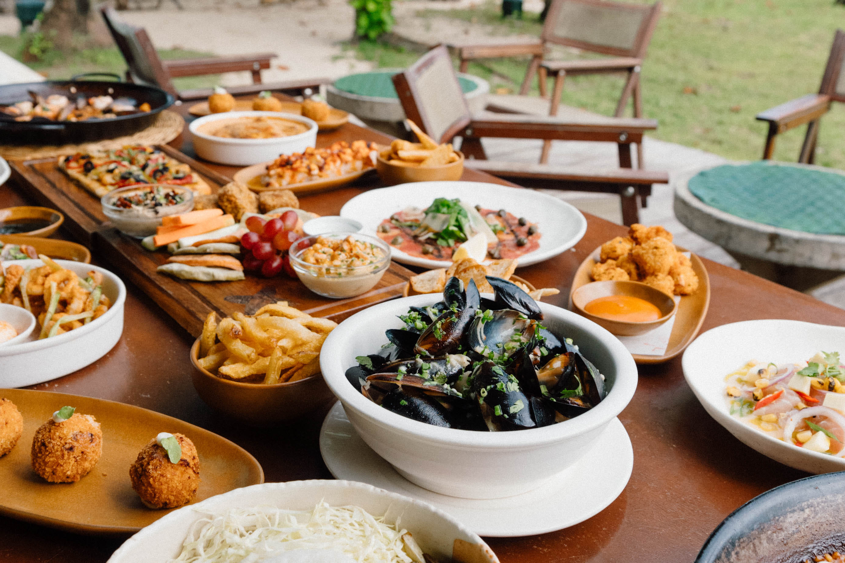 Seafood paella in a pan garnished with aioli, with ceviche and mussels on the table at Bravo Beach Resort Siargao