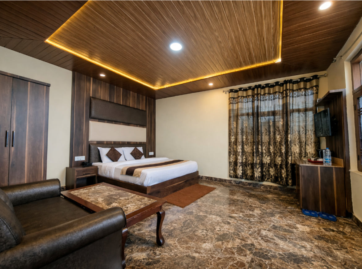 Deluxe Room at Hotel Himdhara with a king-size bed, a sofa, and warm ceiling lights