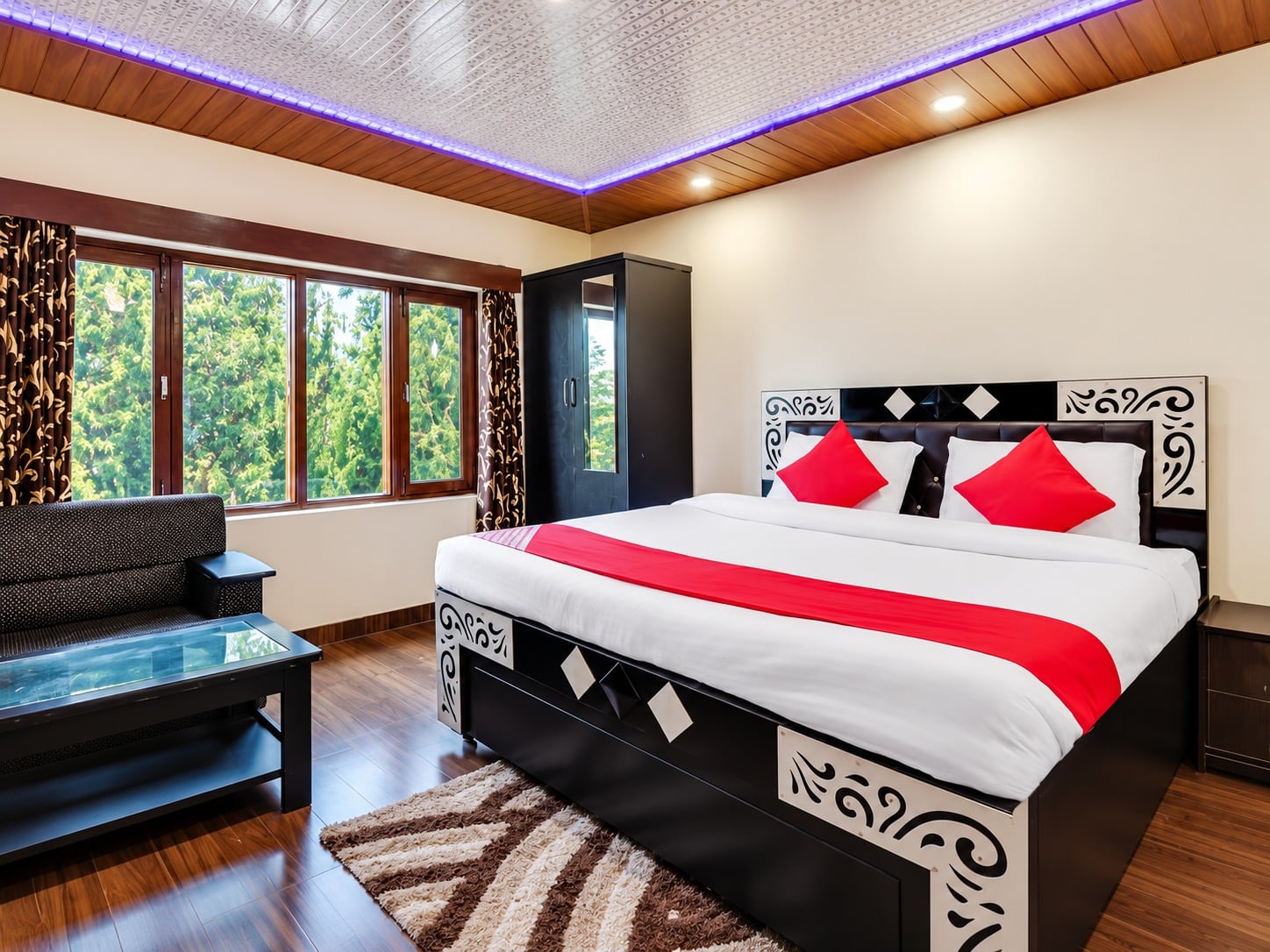A guest room at Hotel Himdhara with a double bed and forest outside the window