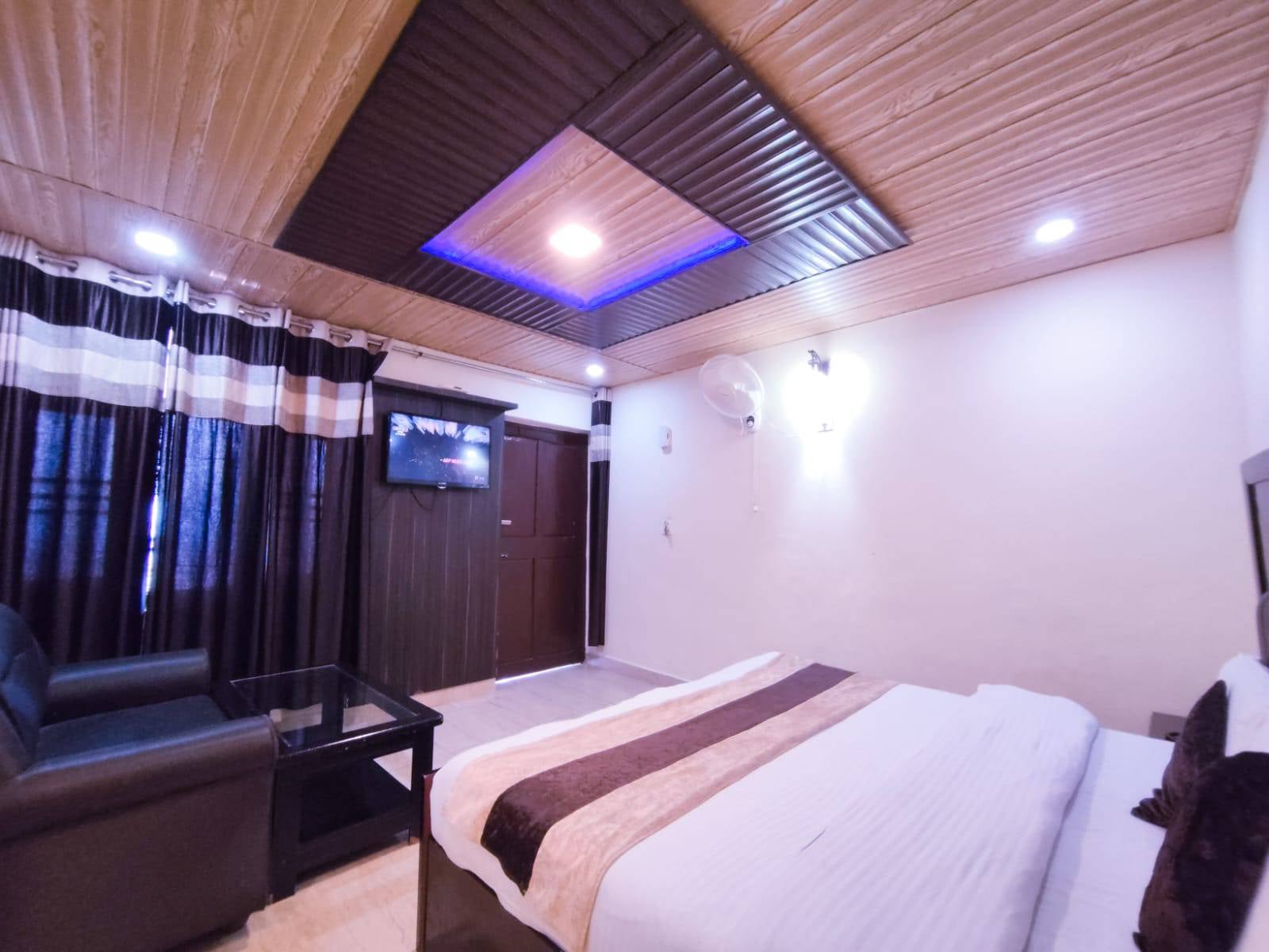 Standard Room at Hotel Himdhara with a wall-mounted TV, an armchair, and curtained windows