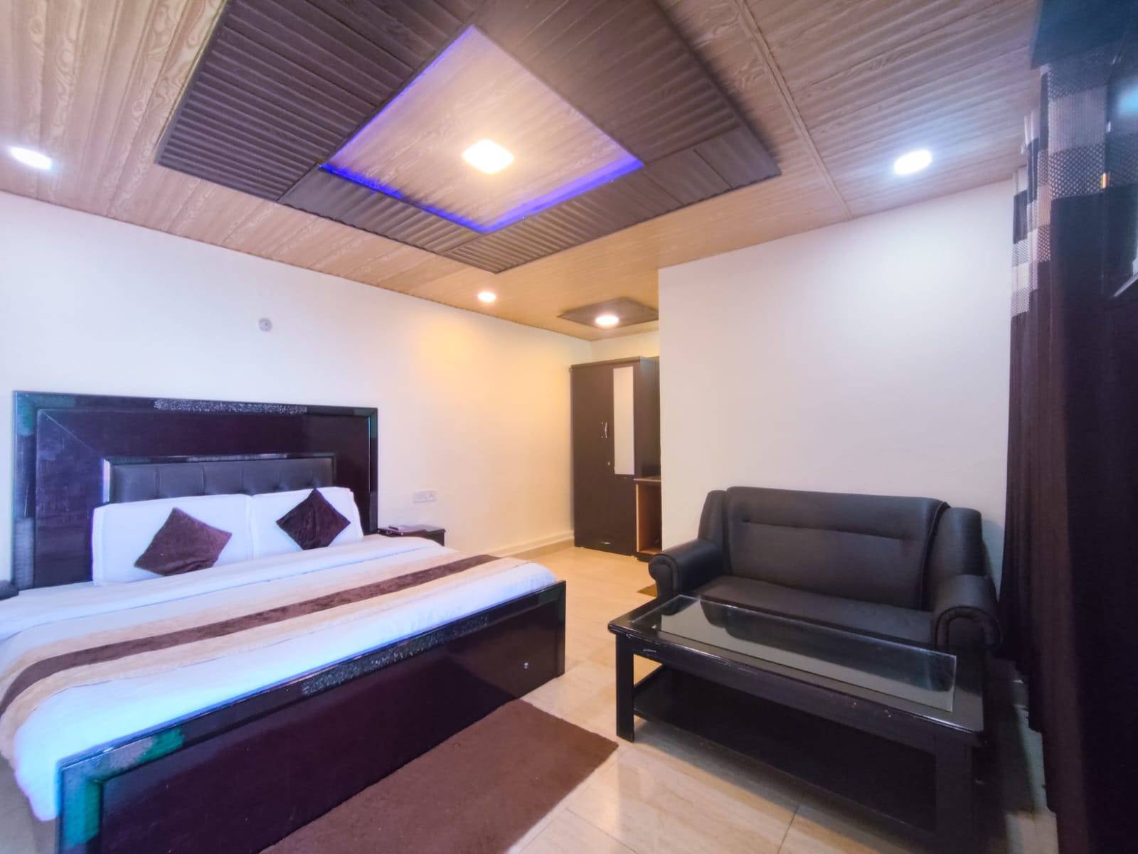 Standard Room at Hotel Himdhara with a double bed, a leather sofa, and a lit wooden ceiling