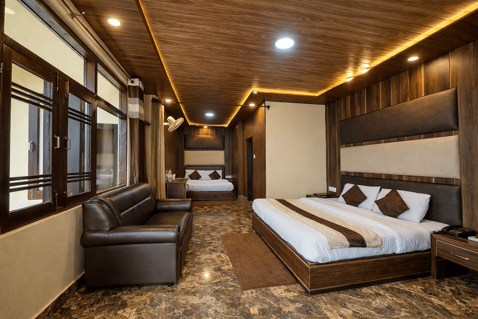 A guest room with a leather sofa at JPT Hotels, Dalhousie