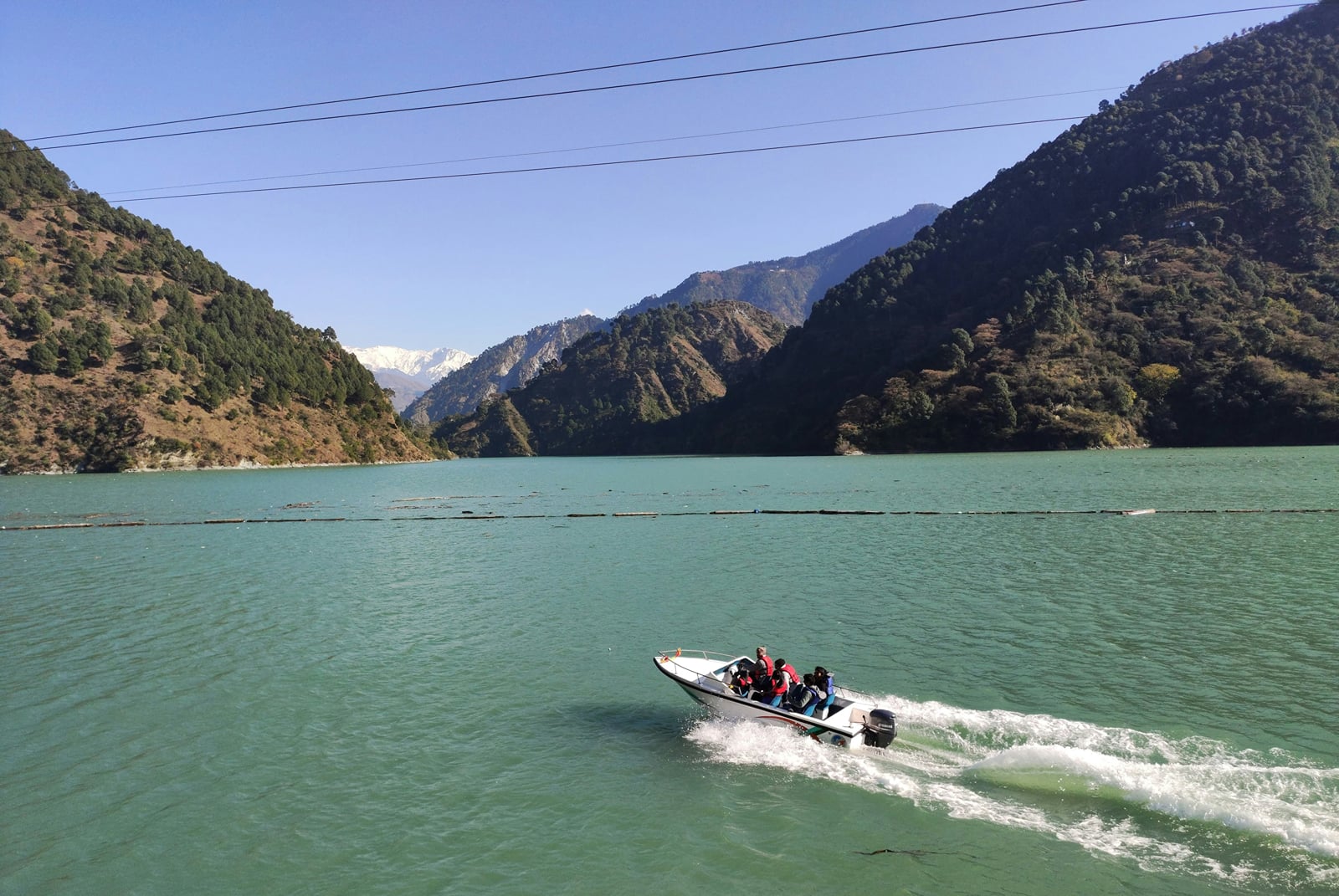 A speedboat on Chamera Lake below forested hills