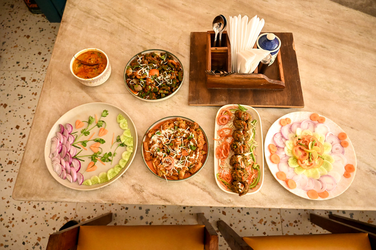 Indian dishes and a fresh salad laid out on a restaurant table