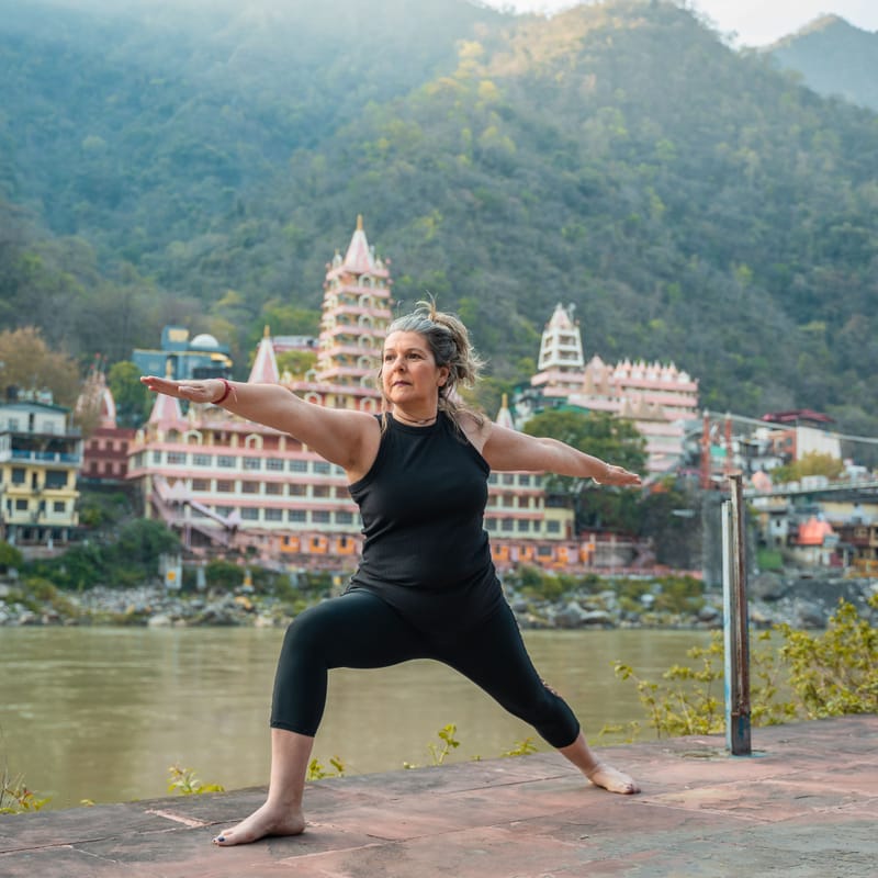 A yoga session on a riverside terrace, with temples across the water