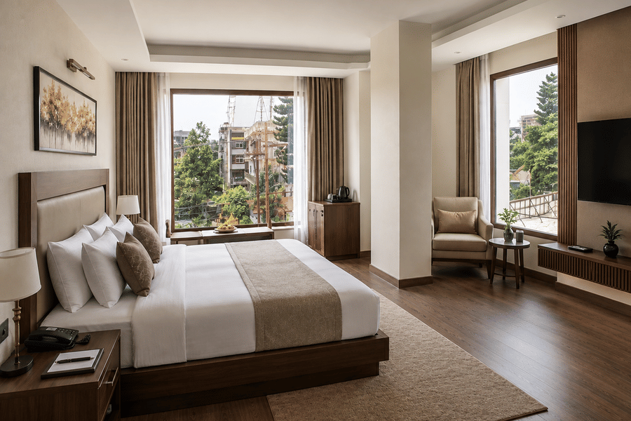 A corner guest room with city-facing windows at Signum Cityscapes, Dehradun