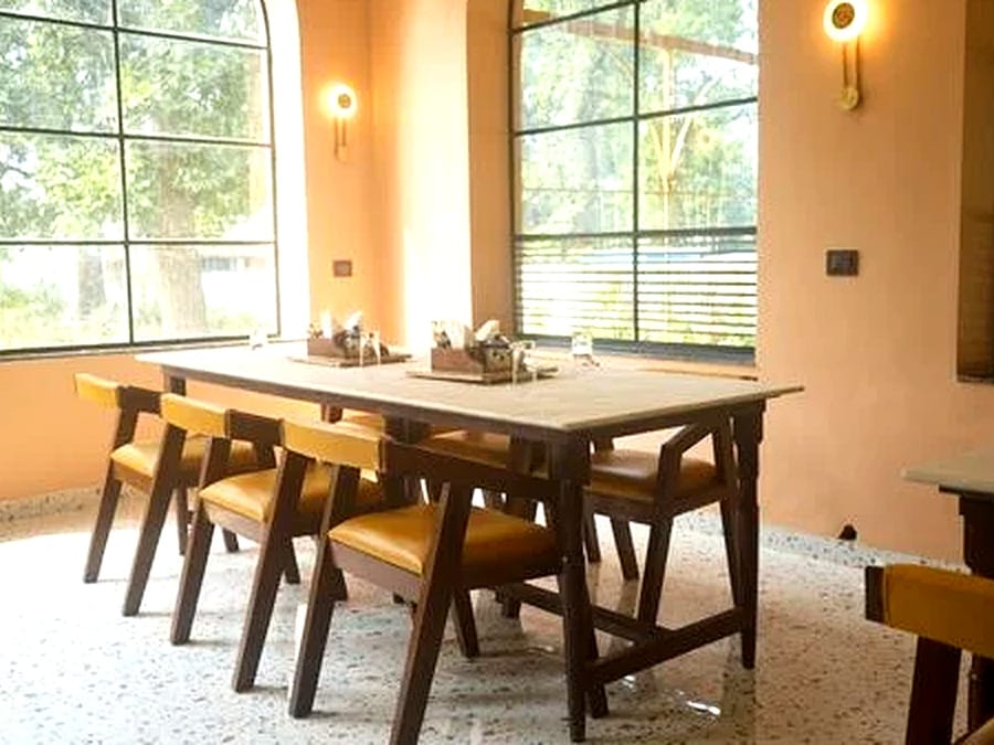 A restaurant table set beside the arched windows at Signum Resort, Bandhavgarh