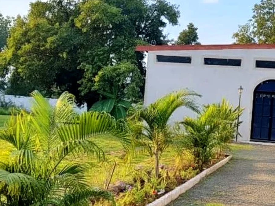 A whitewashed block set behind the lawns at Signum Resort, Bandhavgarh