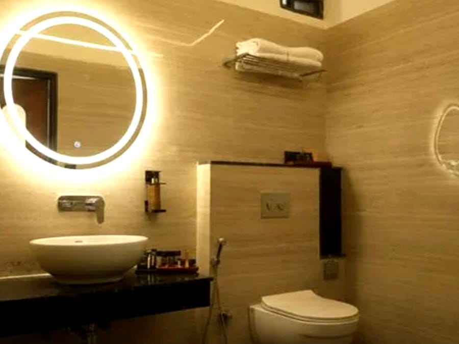 A guest bathroom with a backlit mirror at Signum Resort, Bandhavgarh