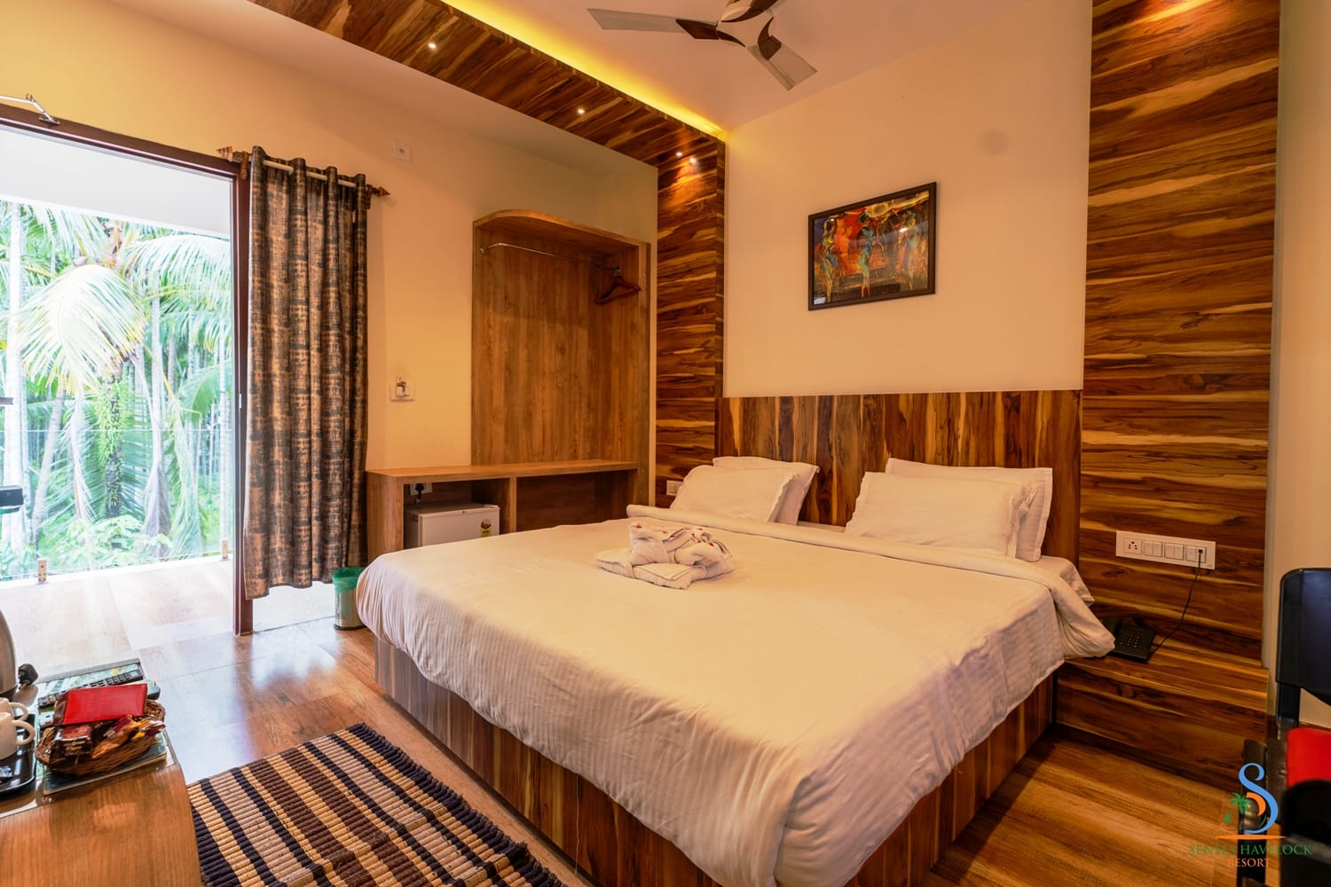 A Deluxe Room with a king bed, timber panelling and a garden-facing glass door