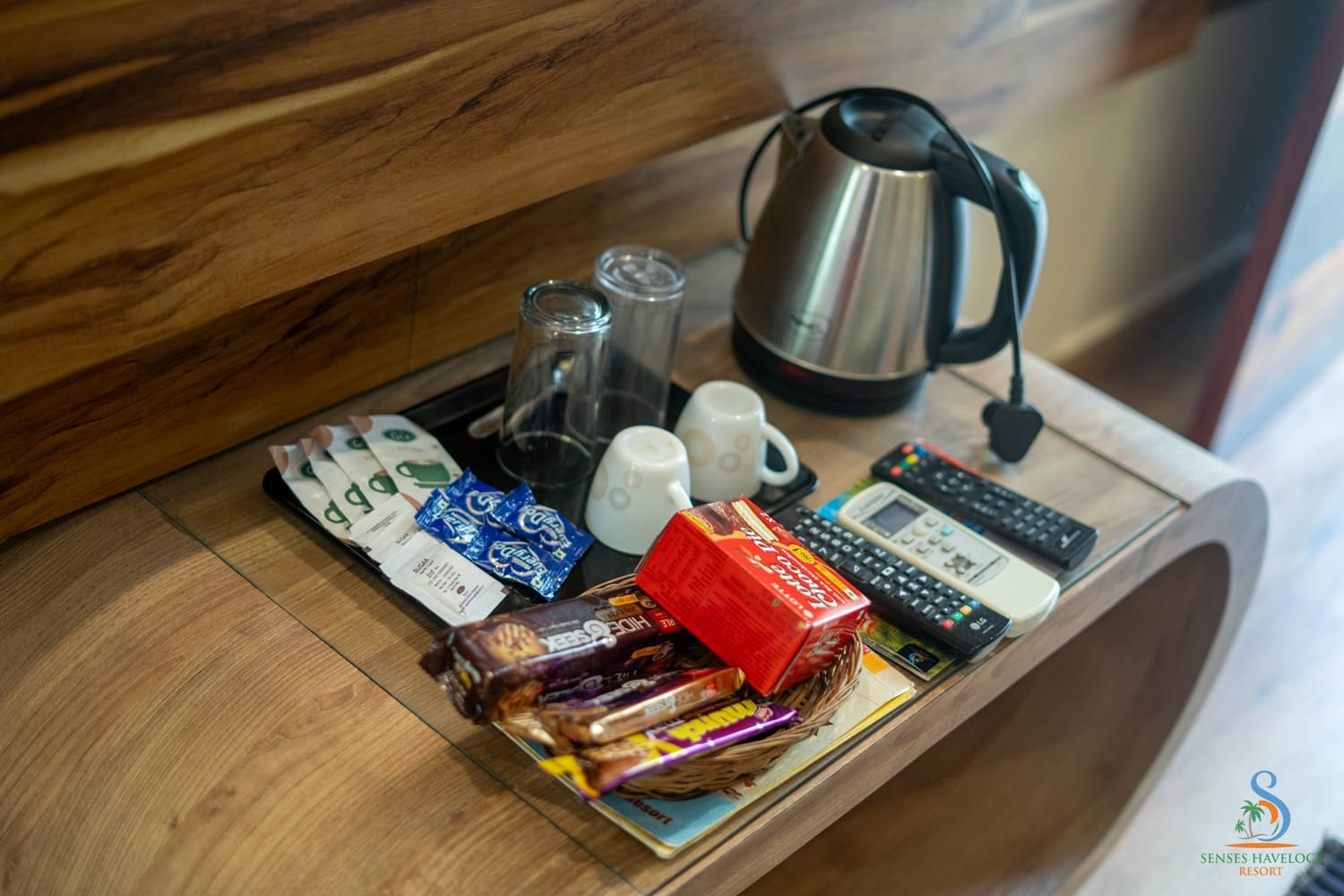 The in-room tea and coffee tray with kettle, cups and a basket of snacks