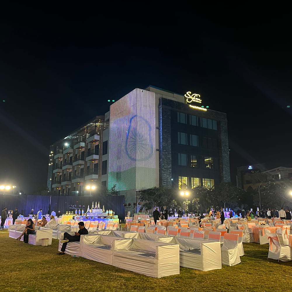 Skyline Resort & Convention Centre facade lit in warm light above the lawn set with round tables for an evening reception