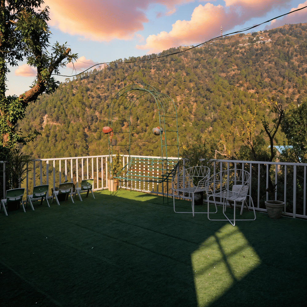 Glass-walled reception lounge terrace at Nazaara Nature Retreat with cushioned seating overlooking the forest at sunset