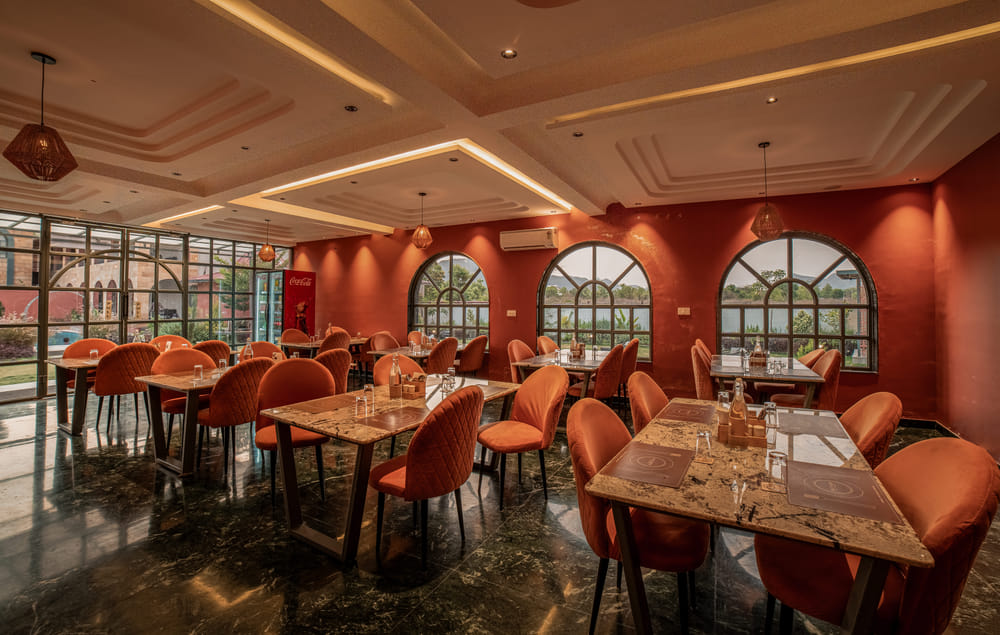 The indoor dining area at Nazaara Fine Dine, Nazaara Hills Retreat, Udaipur, tables set beneath a wooden ceiling.