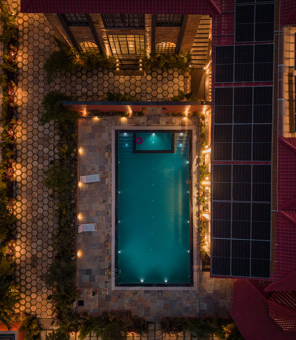 A drone view of the hexagonal pool deck at Nazaara Hills Retreat, Udaipur, lit up against the night sky.
