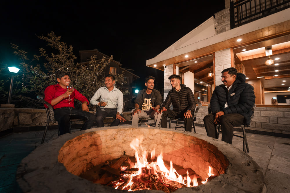 Guests gathered around an evening bonfire at Nazaara Luxe Retreat, seated in a circle beneath the darkening mountain sky.