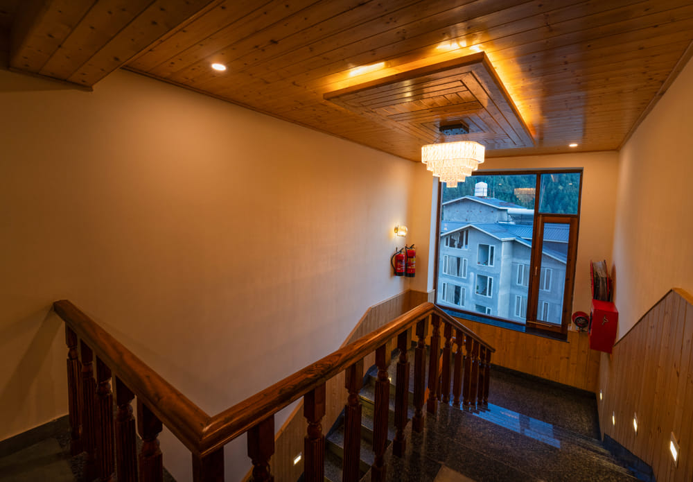 Staircase landing at Nazaara Luxe Retreat with a window opening onto a wide, snow-capped mountain view.
