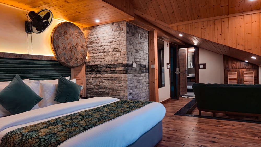 Bed and Jacuzzi tub set against a stone accent wall in the Nazaara Luxe room at Nazaara Luxe Retreat, Manali.