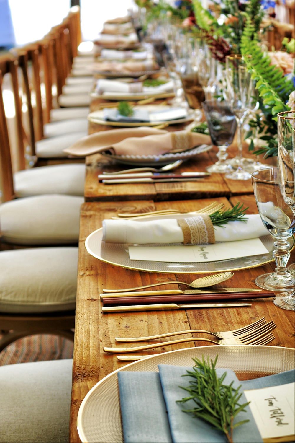 A long wooden dining table laid with linen napkins, gold cutlery, and glassware, set for guests at The Garud Forest, Tadoba