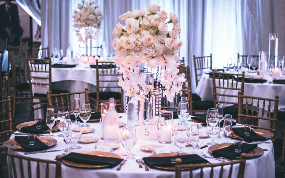 A round banquet table laid with white linen, black chargers, glassware, and a tall floral centrepiece at The Garud Forest, Tadoba