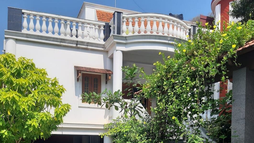 Facade of  Villa Serenity Le Sejour Pondicherry with a swimming pool in front and plants on the side.