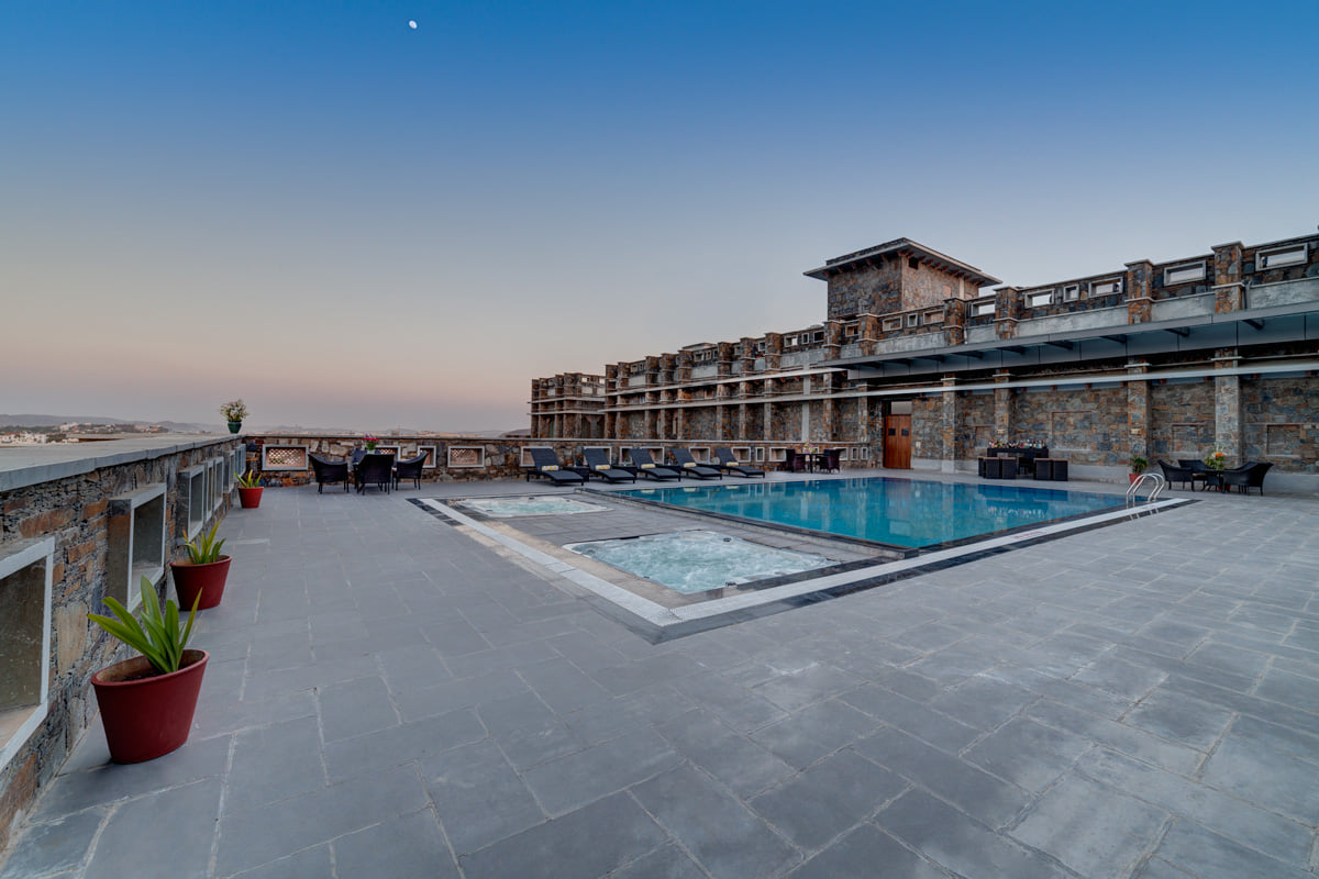 Rooftop pool and Jacuzzi at dusk at Ramada by Wyndham Udaipur Resort and Spa