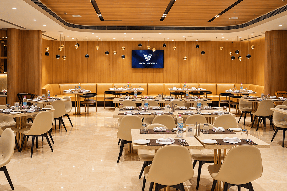 Dining room at Atlas World Café with cream chairs, set tables, and a wood-panelled wall