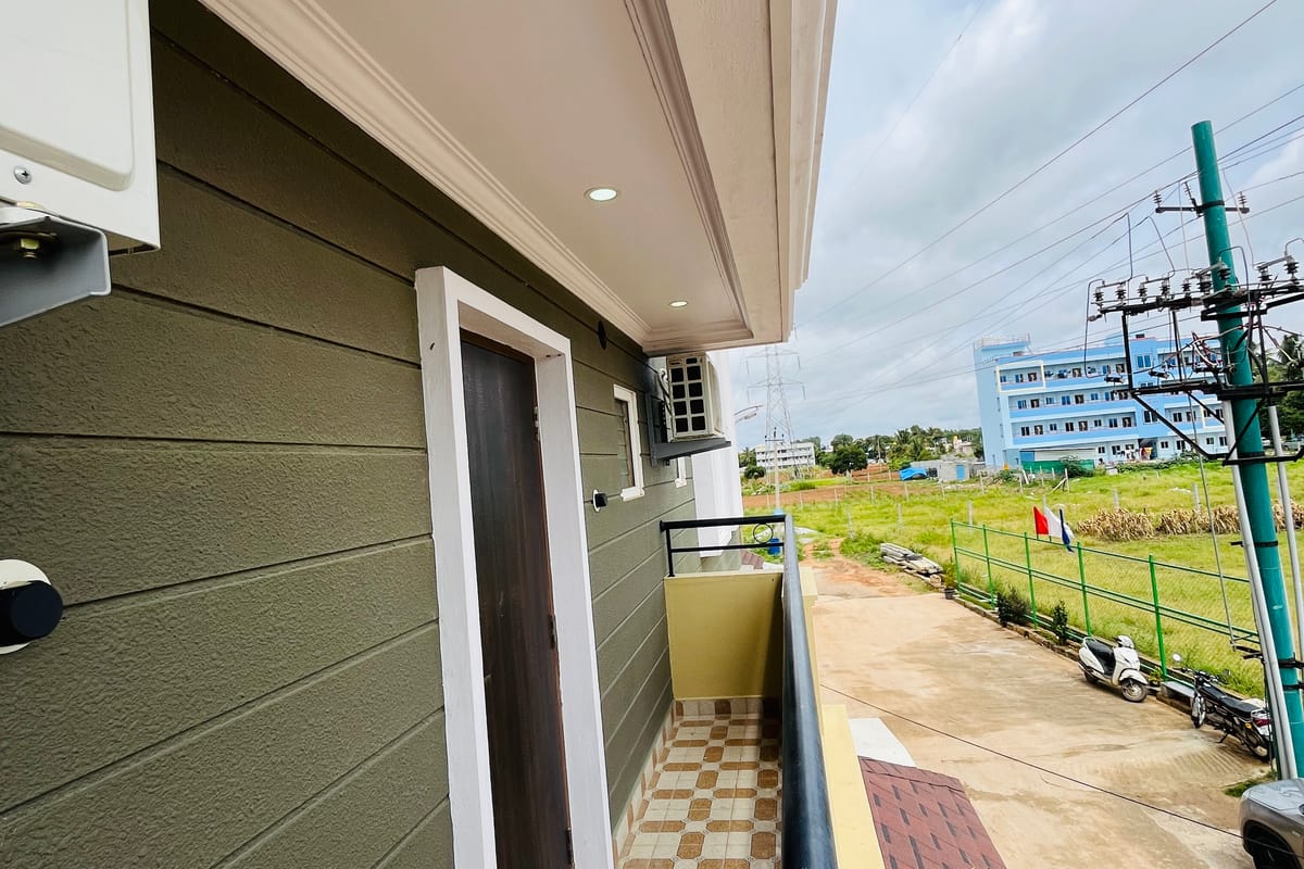 Private balcony of the Standard Balcony Room at Value Inn, Bangalore Airport with chequered flooring and views over open green fields