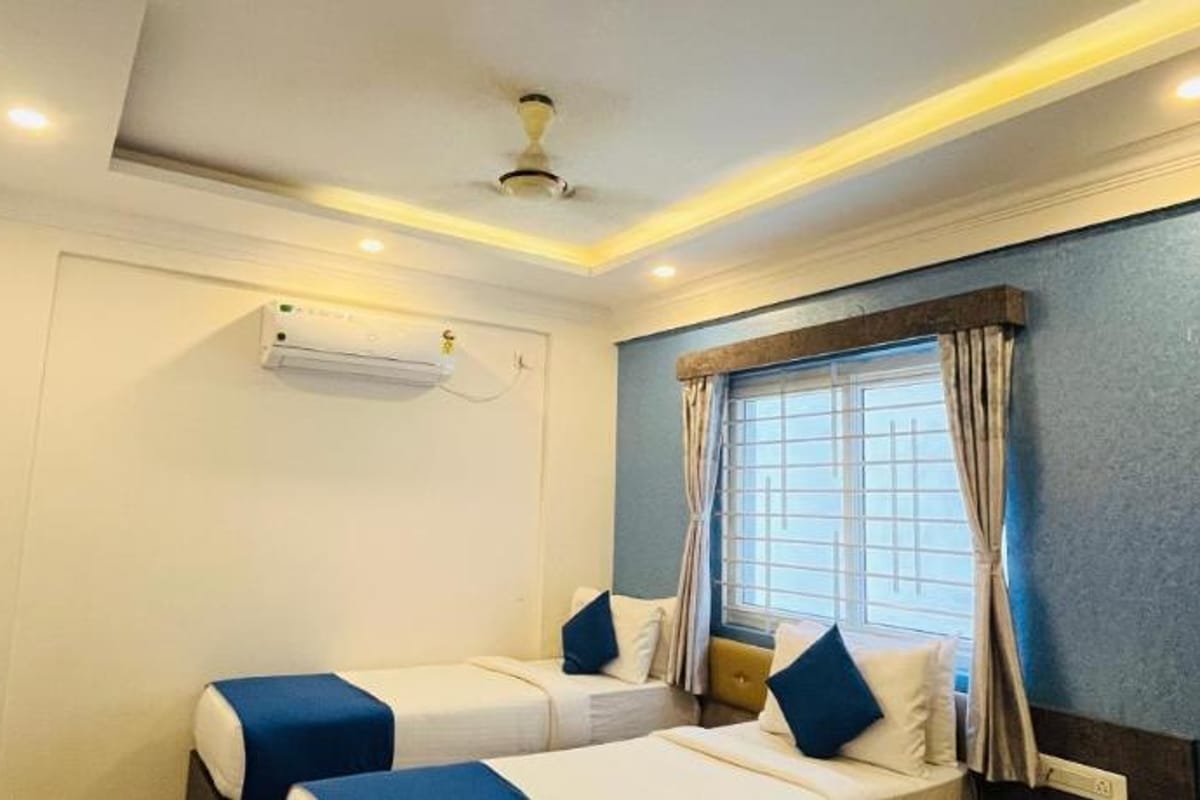 Standard AC Twin Room at Value Inn, Bangalore Airport with 2 single beds, a wall mounted air conditioner, and warm cove ceiling lighting