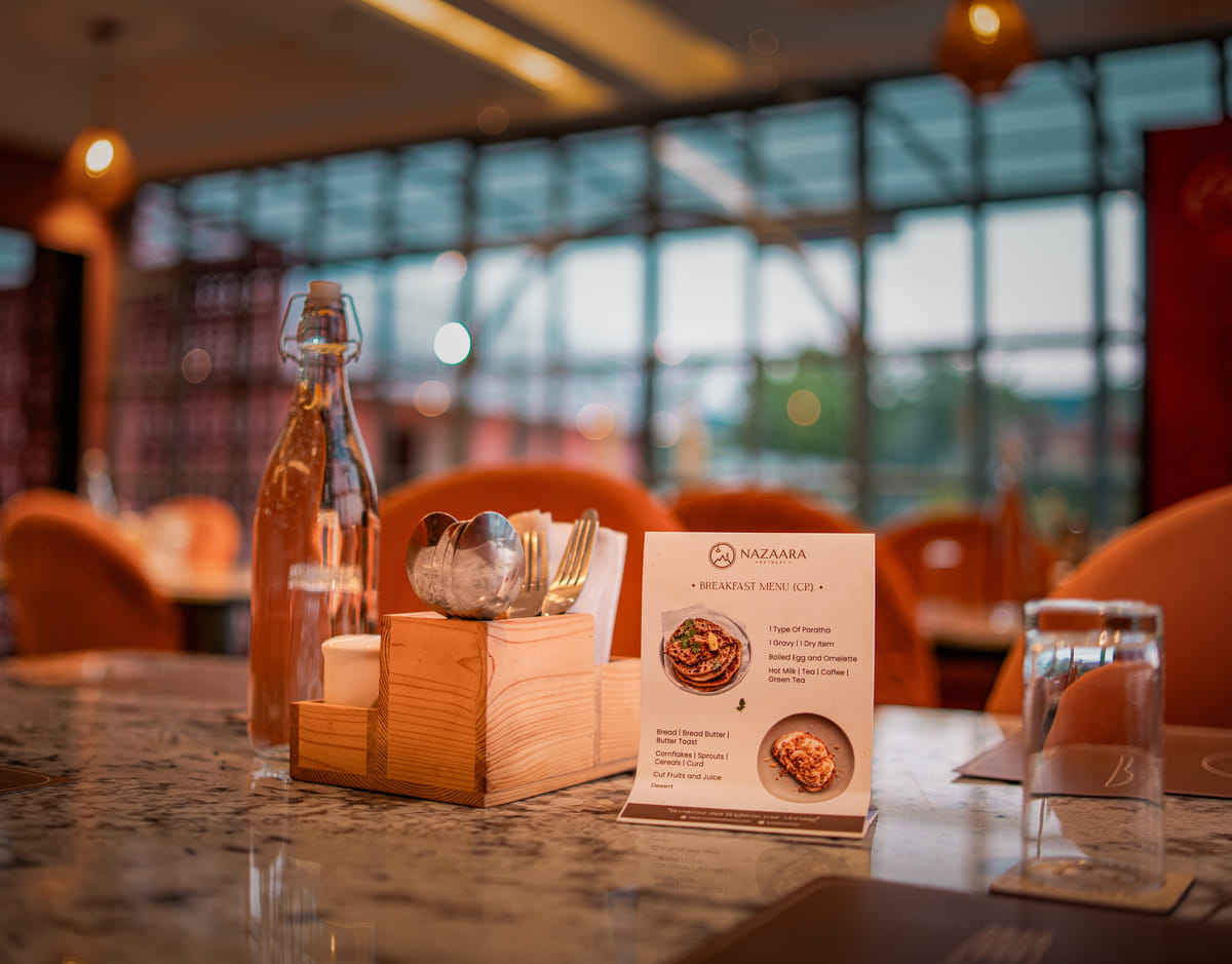 A table setting at Nazaara Fine Dine restaurant, Nazaara Hills Retreat, Udaipur, arranged for a premium indoor meal.