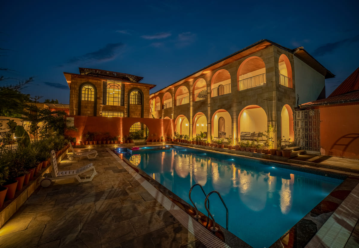 Nazaara Hills Retreat, Udaipur, poolside loungers lit at night