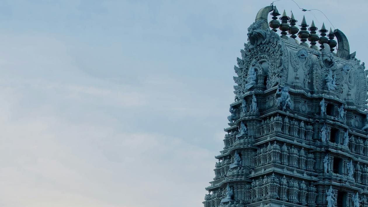 A temple with carvings on the wall set against a gloomy sky.