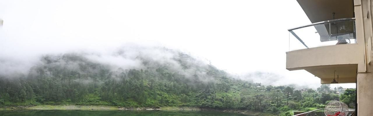 View from the hotel facing a serene green lake and forested hills.