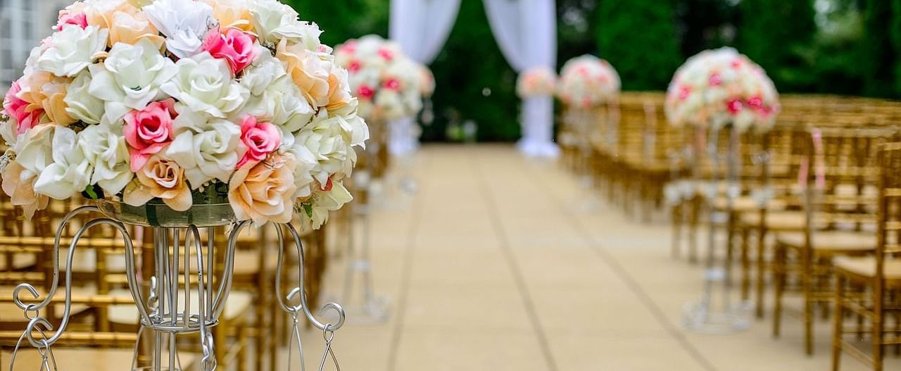 Elegant outdoor wedding ceremony setup with floral arrangements and an aisle.