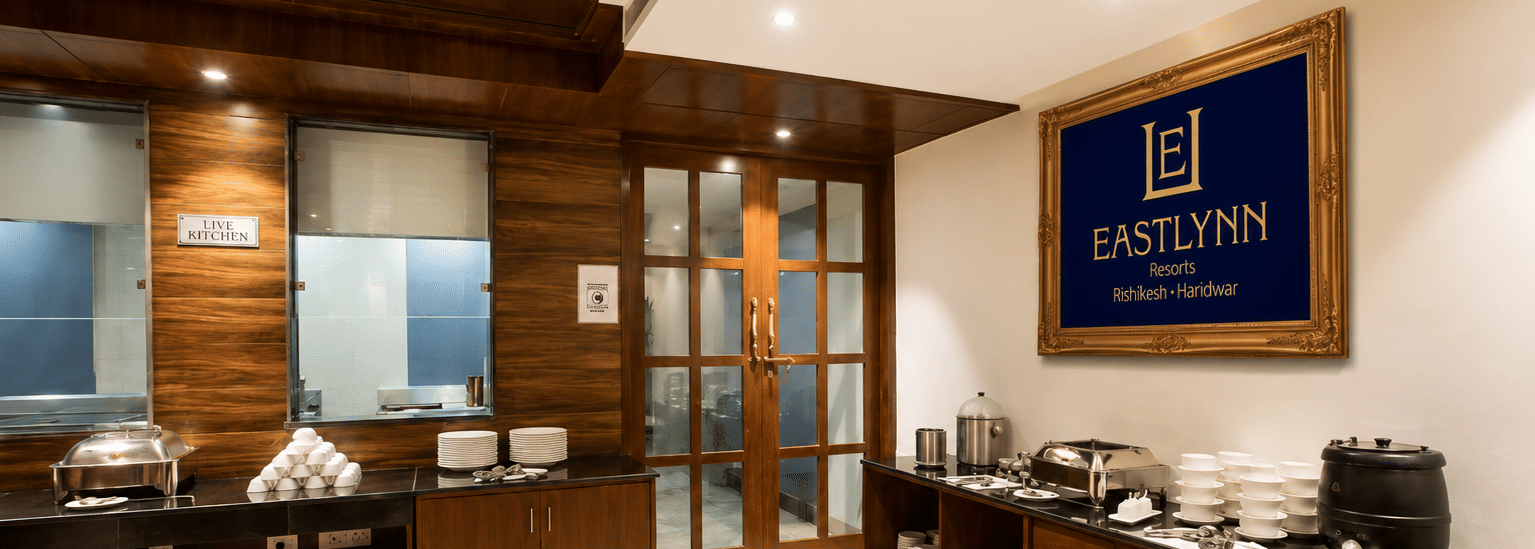 Buffet counter with dark wood cabinetry and serving dishes at Eastlynn Resort, Rishikesh.