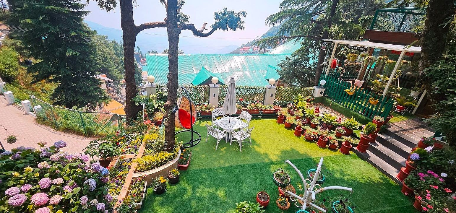 Charming garden area with vibrant flowers, seating arrangements, and a scenic hillside view surrounded by lush greenery -Mongas Hotel & Resort, Dalhousie